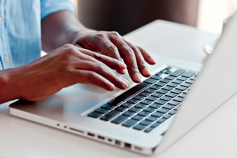 Hands typing on laptop